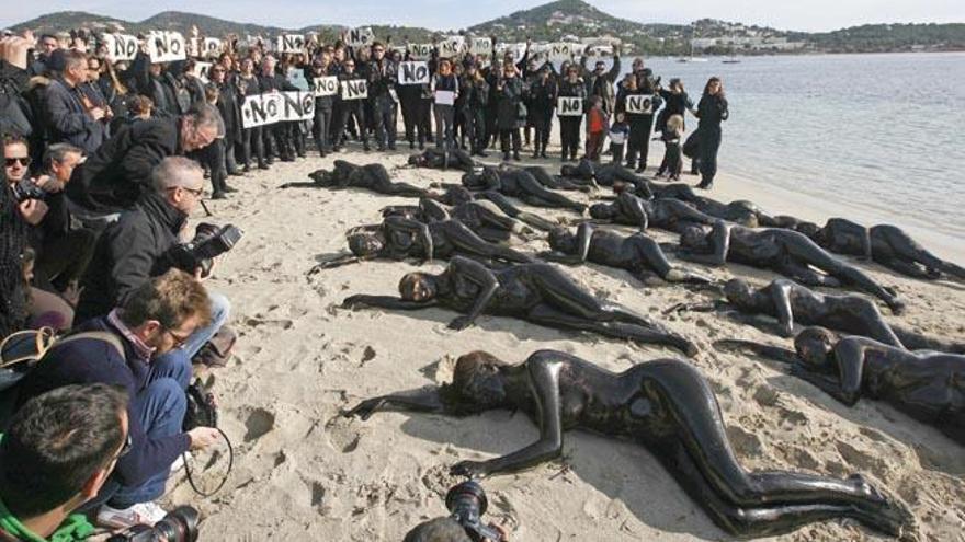 Los activistas, tumbados en el suelo, de fondo, personas vestidas de negro con carteles.
