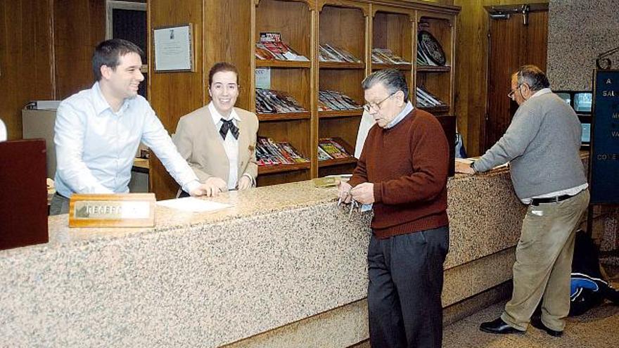 Unos turistas en la recepción de un hotel en Ourense.