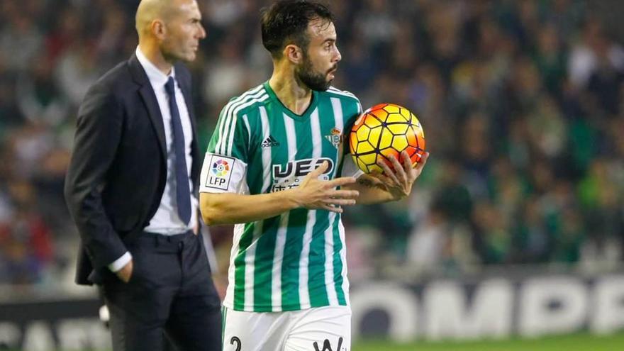 Molinero sujeta el balón durante su etapa en el Betis, con Zidane al fondo.