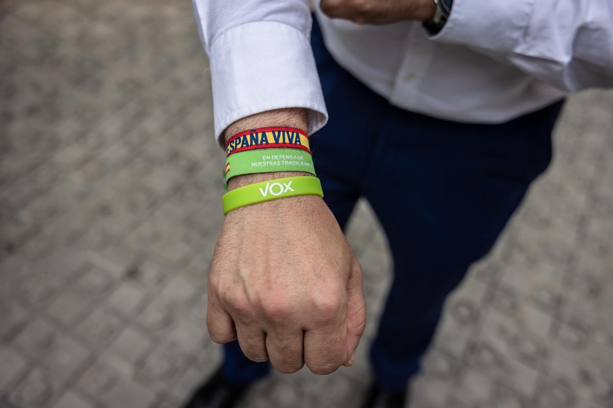 Un hombre muestra las pulseras con la bandera española y de Vox. 