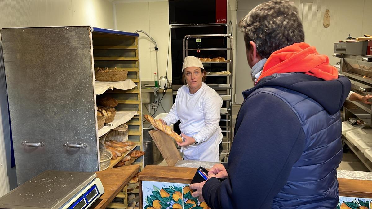 Esther Masana mostra una barra de pa del nou forn Ca la Xata d'Estamariu (Alt Urgell) a un client