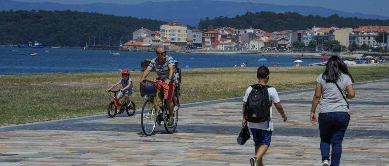 Viandantes en el tramo del paseo marítimo de Vilagarcía que aún sigue con el suelo de baldosas. // I. Abella