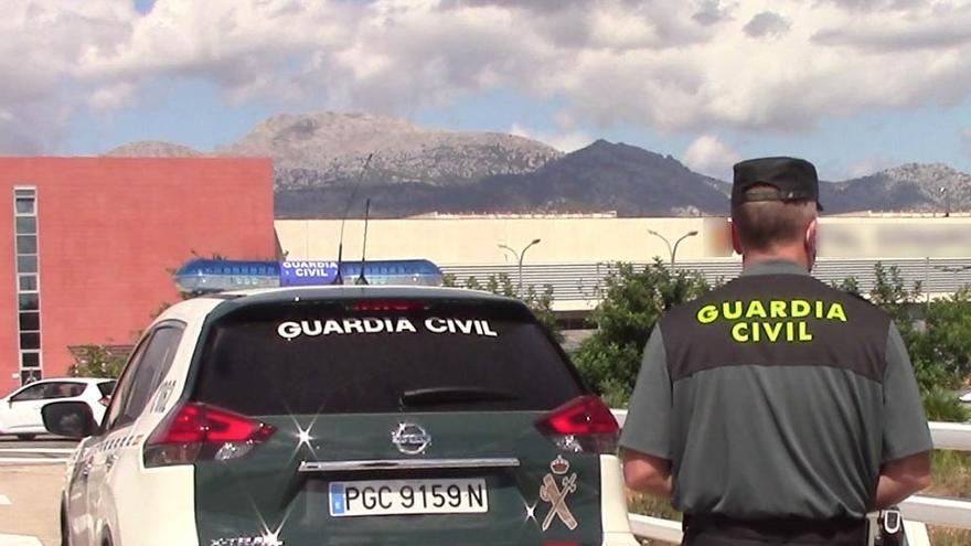 Archivo - Un vehículo de la Guardia Civil y un agente de espaldas.