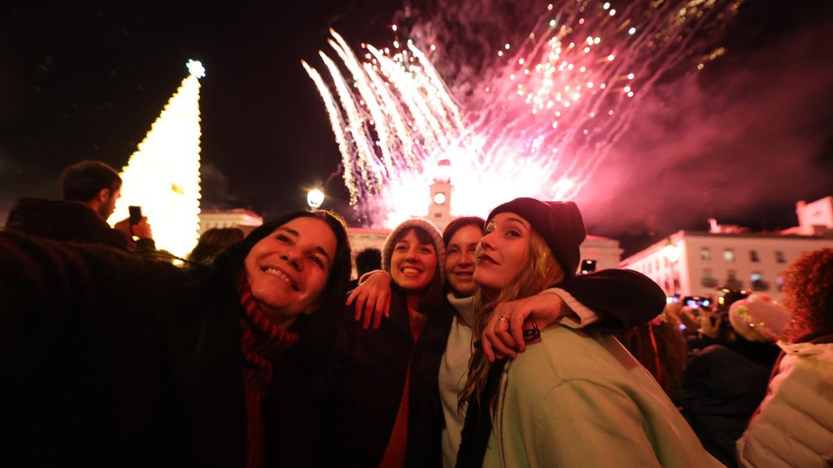 Cuatro mujeres se hacen un selfie con los fuegos artificiales de fondo en la Real Casa de Correos tras las Campanadas de Fin de Año 2022.