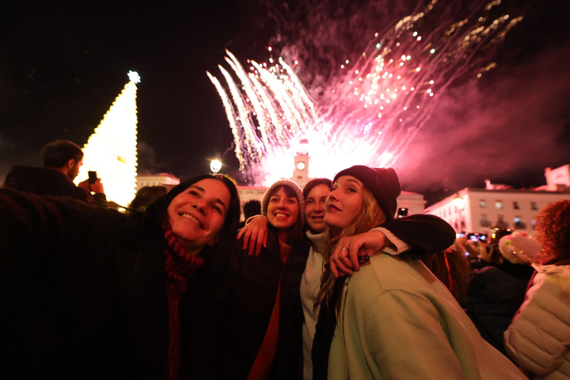 Cuatro mujeres se hacen un selfie con los fuegos artificiales de fondo en la Real Casa de Correos tras las Campanadas de Fin de Año 2022.