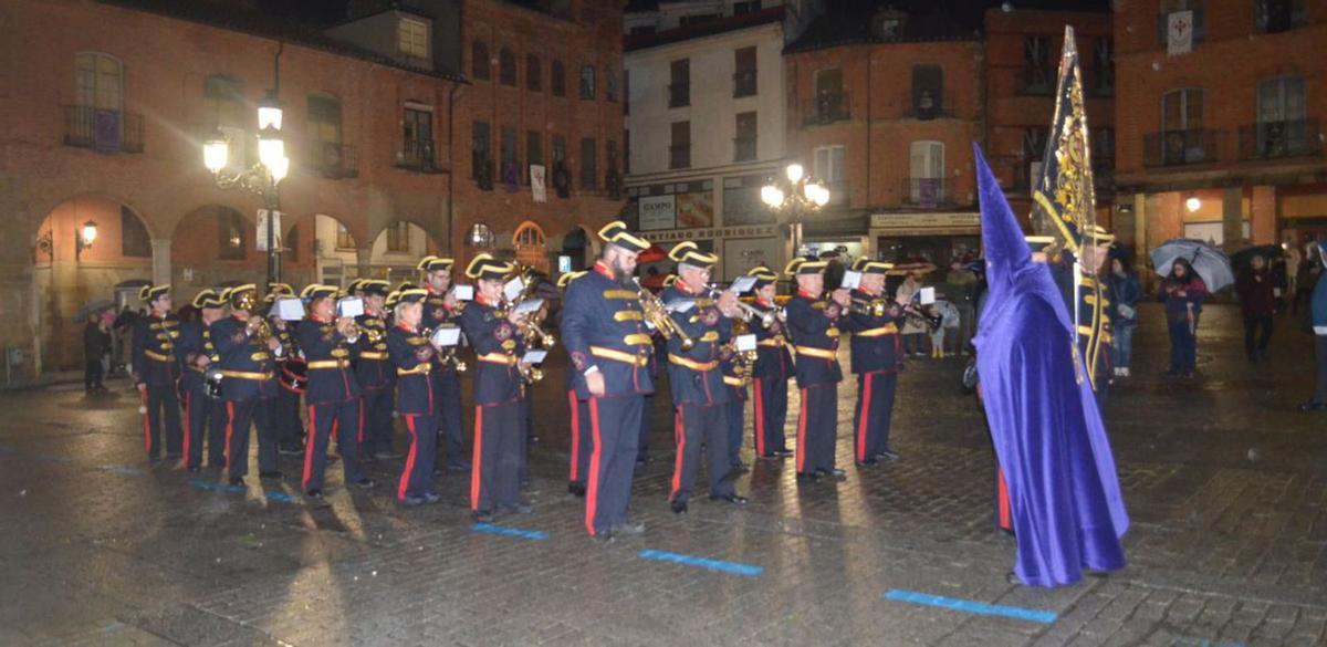 La Agrupación Musical de Astorga y un cofrade de la Vera Cruz, en la Plaza Mayor. | E. P.