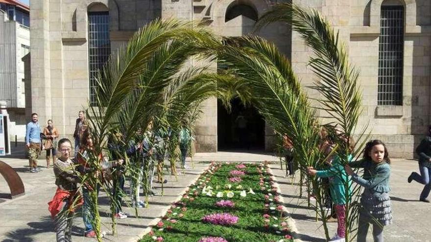 Los niños de catequesis muestran su alfombra de flores