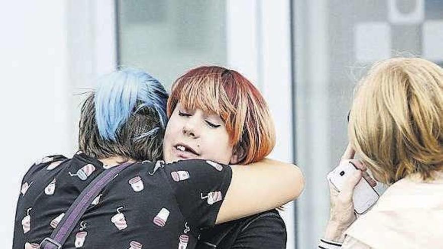 Una joven que resultó con heridas leves en el accidente del autobús, Alba Caride, se abraza con una amiga en la puerta del hospital.