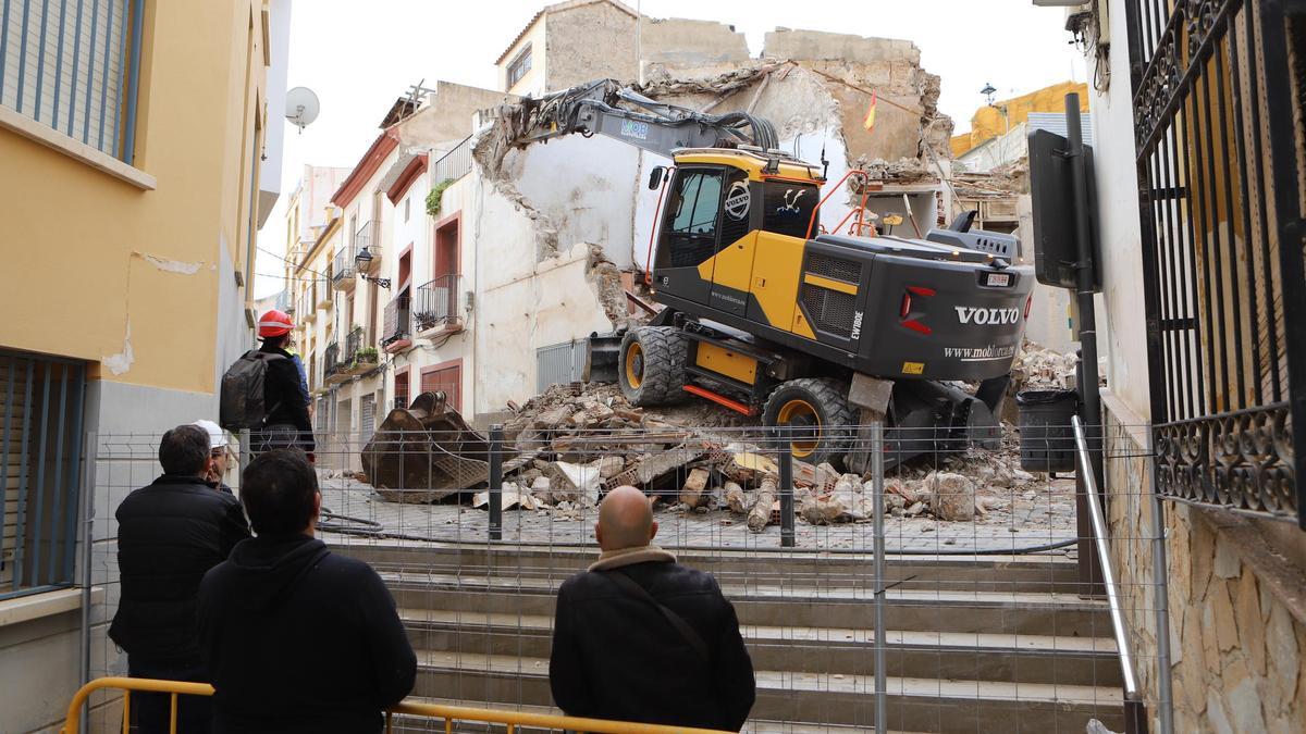 Varios vecinos contemplan el derribo de la casa junto al porche de San Antonio.