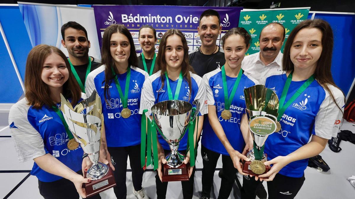 Por la izquierda, Amaia Torralbo, Jonathan Martínez, Jana Villanueva, Mónica Ospina, Laura Álvarez, César González, director técnico del CB Oviedo; Laura Soto, Nicolás García y Laura Garijo, con los tres trofeos de campeonas de la Copa Iberdrola, en el Corredoria Arena.