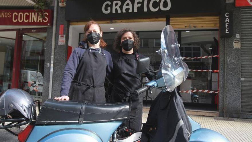 Montse y Sandra, propietarias del Bar Gráfico, en frente de su bar con una moto. //IÑAKI OSORIO