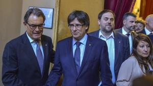 Mas saluda a Puigdemont ante la mirada de Junqueras en el Parlament tras la sesión sobre la moción de confianza.