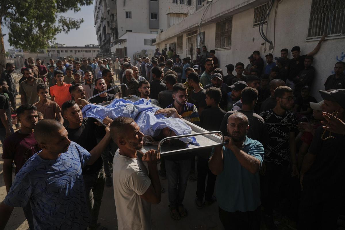 Palestinians carry the body of a person who was killed while trying to reach aid trucks entering northern Gaza Strip through the Zikim crossing with Israel, at Shifa Hospital in Gaza City, Wednesday, Aug. 6, 2025. (AP Photo/Jehad Alshrafi)