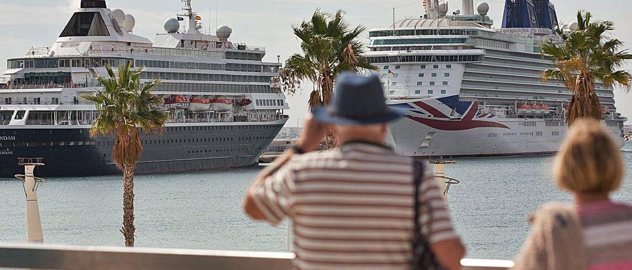 Dos cruceristas observan dos barcos amarrados en el puerto de Alicante en una imagen de archivo. ALEX DOMÍNGUEZ