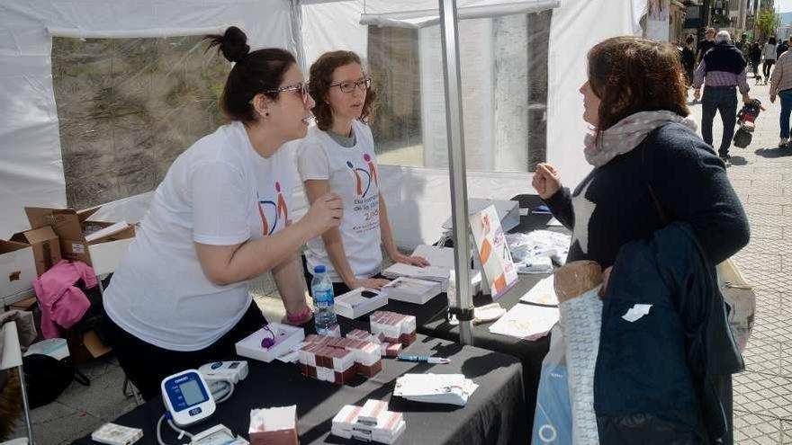 Dos profesionales de la salud resuelven consultas en la mesa informativa instalada ayer. // R. Vázquez