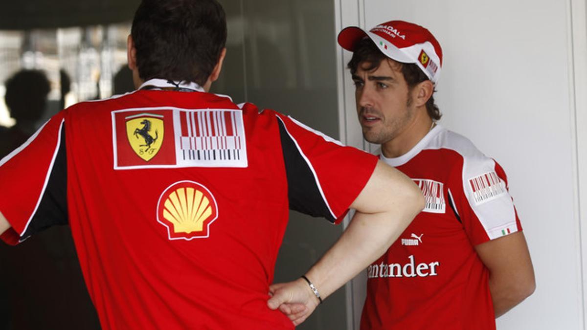 Alonso intercambia impresiones con un miembro del equipo mecánico de Ferrari , esta mañana en el circuito brasileño de Interlagos.