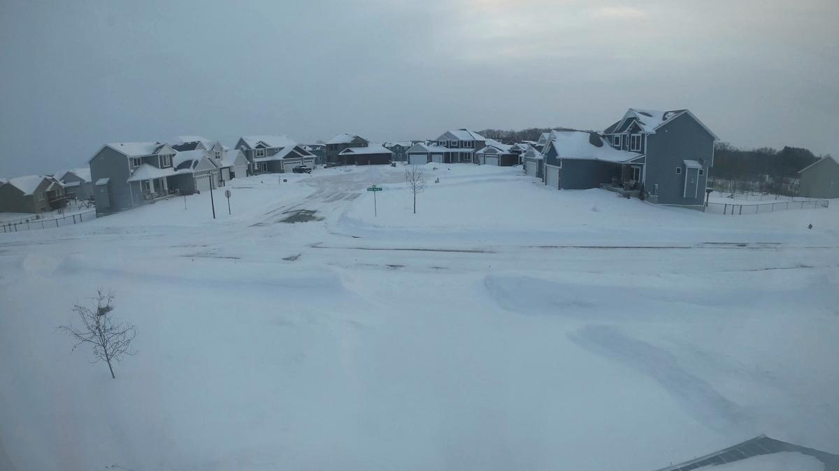 A view of buildings and a street covered in snow during a winter storm in Forest Lake