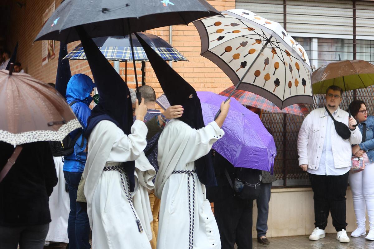 Nazarenos de La Estrella se protegen de la lluvia.
