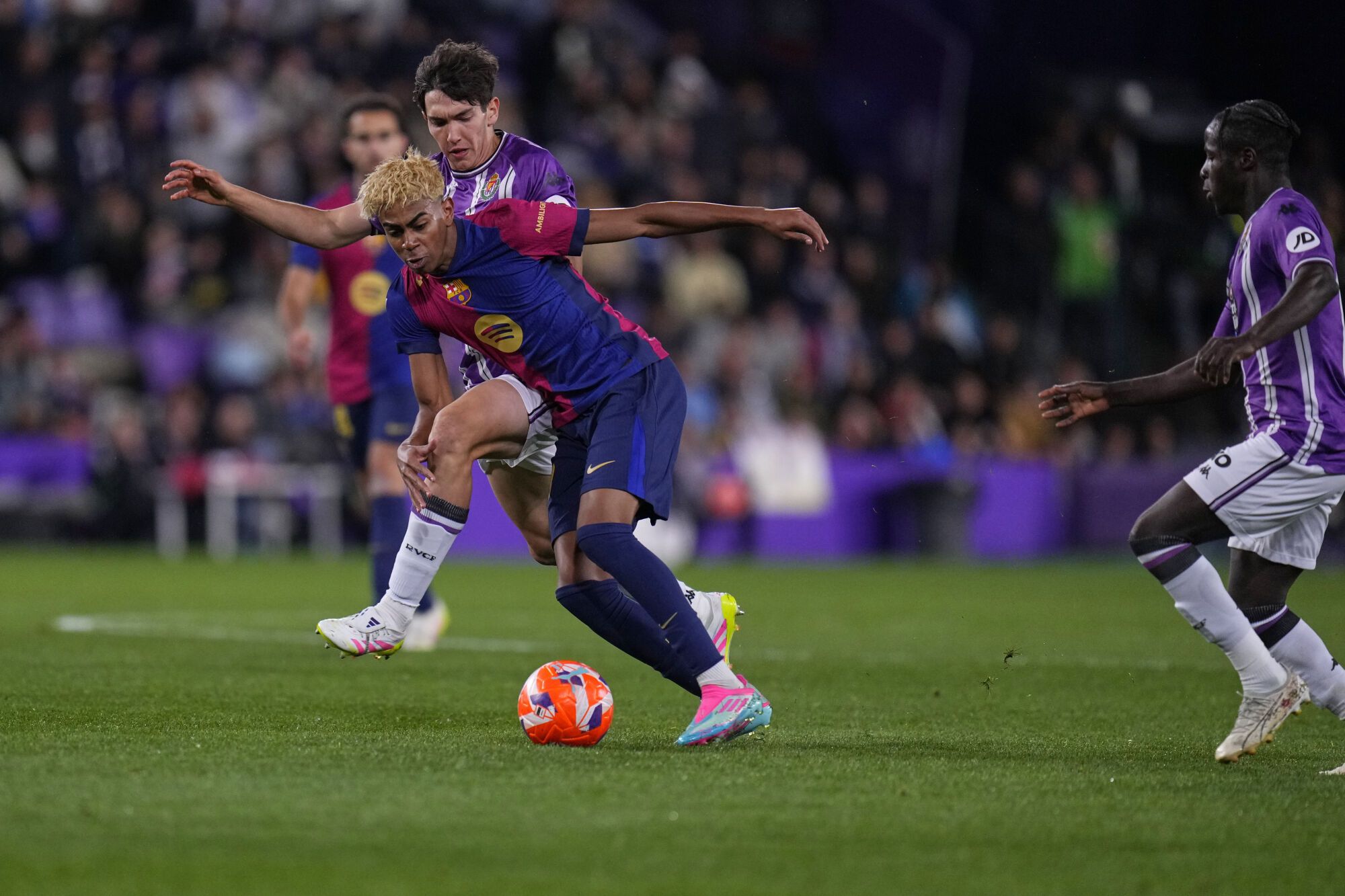 Barcelona's Lamine Yamal, centre, and Valladolid's Antonio Candela, left, challenge for the ball during the Spanish La Liga soccer match between Valladolid and FC Barcelona at the Jose Zorrilla stadium in Valladolid, Spain, Saturday, May 3, 2025. (AP Photo/Manu Fernandez)