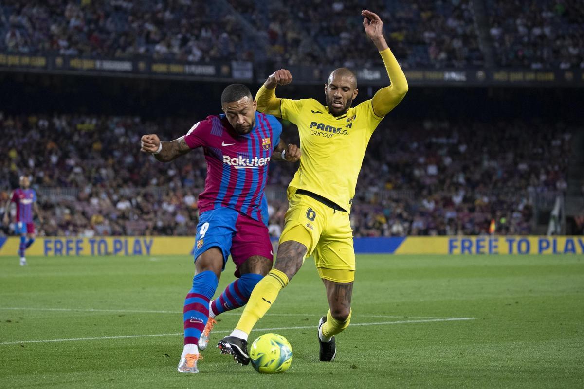 BARCELONA, 22/05/2022.- El delantero del Barcelona Memphis Depay (i) pelea un balón con Etienne Capoue, del Villarreal, durante el partido correspondiente a la jornada 38 de Liga en Primera División que FC Barcelona y Villarreal CF han disputado hoy domingo en el Camp Nou, en Barcelona. EFE/Quique García