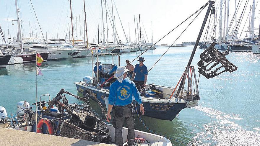 Operarios extraen ayer un carrito del fondo del mar.