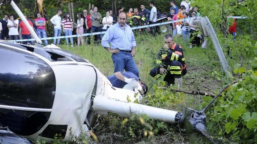 Un investigador y un miembro de Emergencias de Vilagarcía examinan el helicóptero siniestrado. noé parga