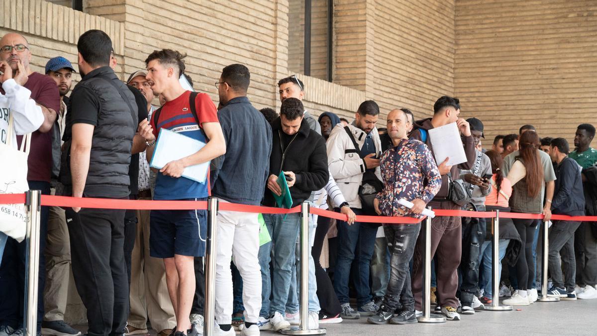 Varias personas hacen fila en el Ayuntamiento de Zaragoza para solicitar los papeles de reglarización, en una imagen de archivo