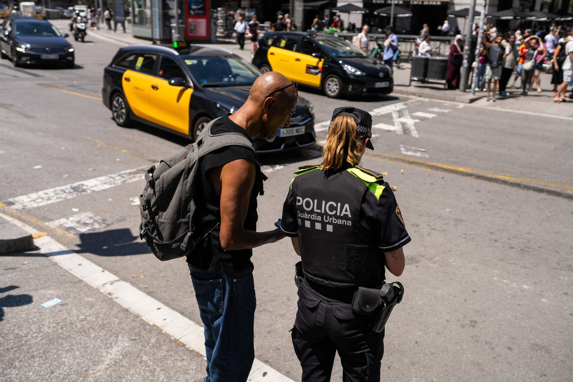 Una agente de la Guardia Urbana con un peatón en el centro de Barcelona.