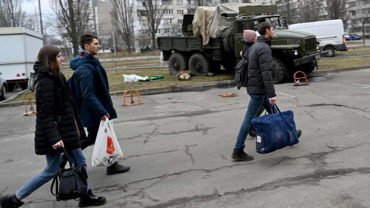 Ciudadanos pasan junto a los cuerpos de los militares rusos que vestían uniformes de servicio ucranianos que yacían al lado y dentro de un vehículo después de que les dispararan como parte de un grupo de asalto durante una escaramuza en la capital ucraniana de Kiev el 25 de febrero de 2022.