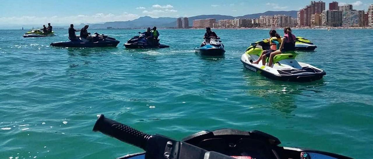 Un grupo de usuarios de motos acuáticas ante los bloques de apartamentos queperfila la bahía de Cullera. | LEVANTE-EMV