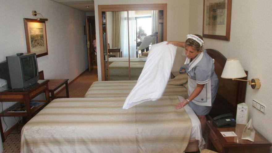 Una mujer hace la cama en un hotel.