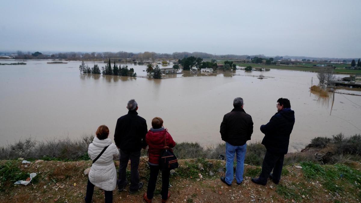 Varias personas observan el desbordamiento del río Ebro.