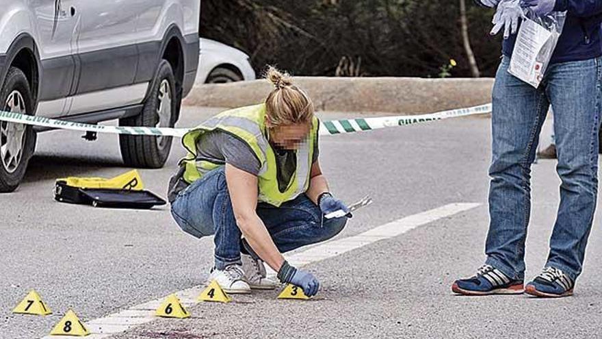 Una agente de la Guardia Civil examina el lugar donde se cometiÃ³ el crimen.