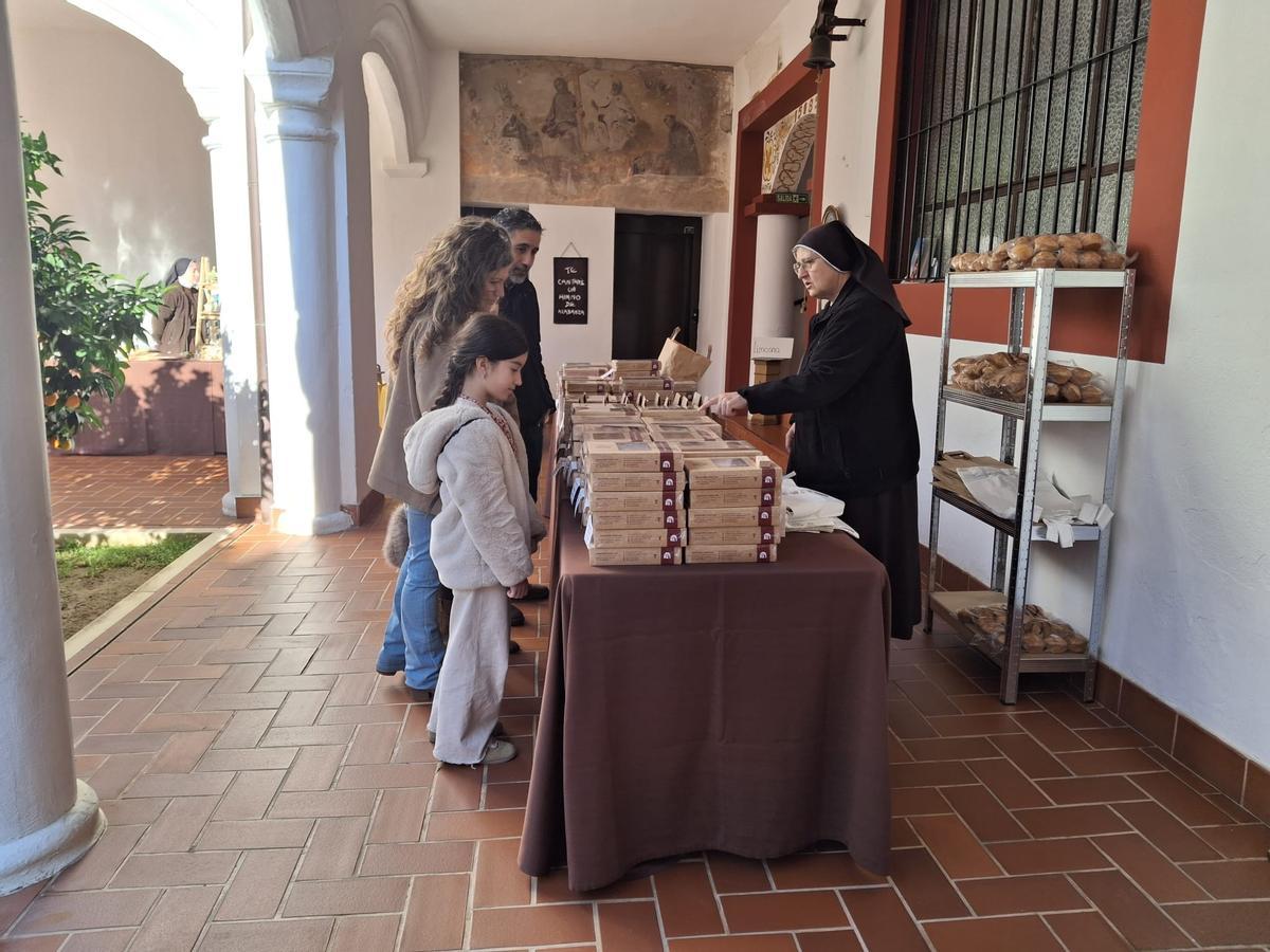Una familia observa la mesa con dulces elaborados en el convento.