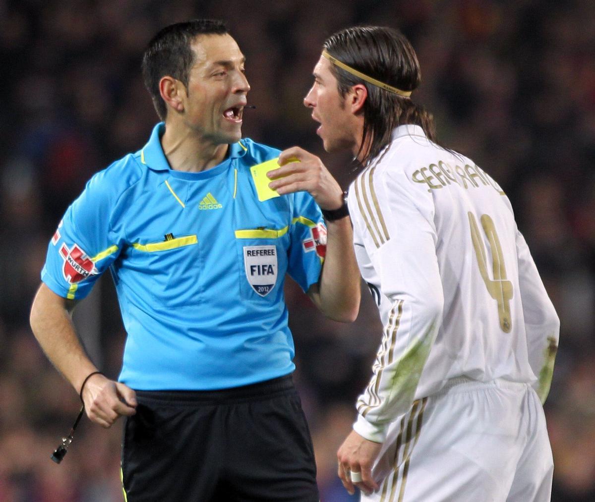 .- El árbitro del partido Fernando Teixeira Vitienes (i) muestra tarjeta amarilla al defensa del Real Madrid, Sergio Ramos (d)
