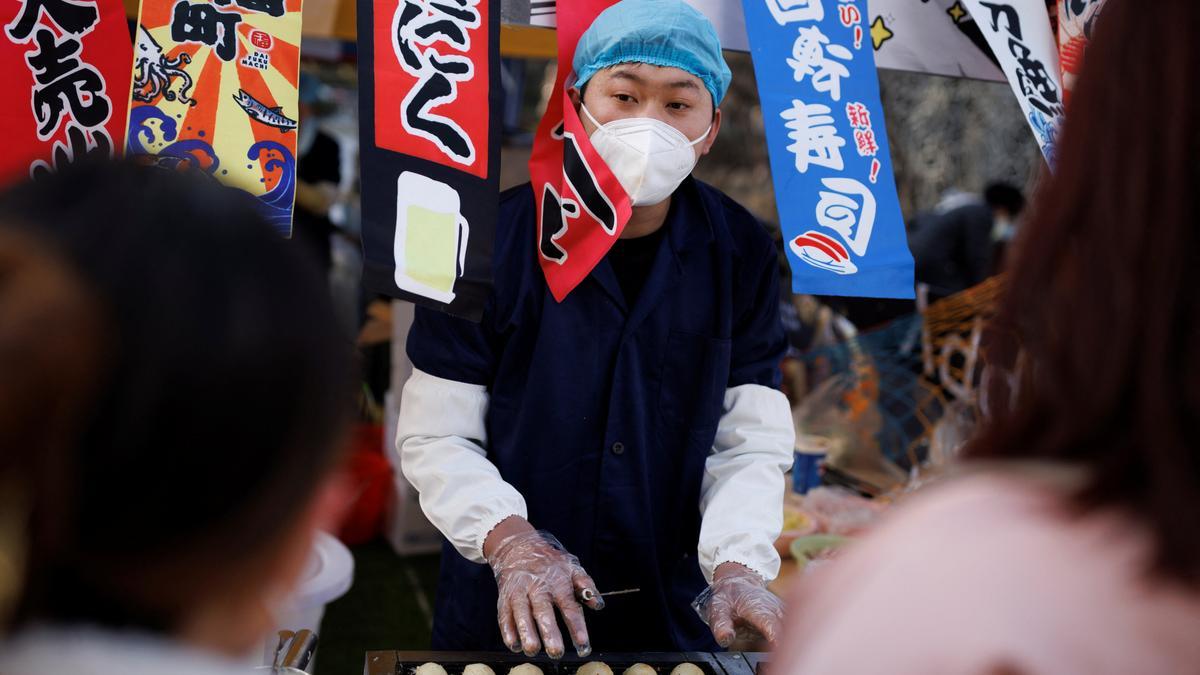 Un hombre vende comida callejera en un distrito comercial mientras China regresa al trabajo a pesar de los continuos brotes de la enfermedad por coronavirus (COVID-19) en Beijing, China.