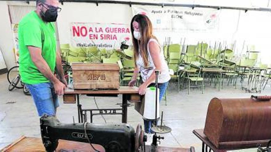 Dos participantes en el proyecto solidario transportan máquinas de coser que viajan a Siria. | ANTONIO AMORÓS