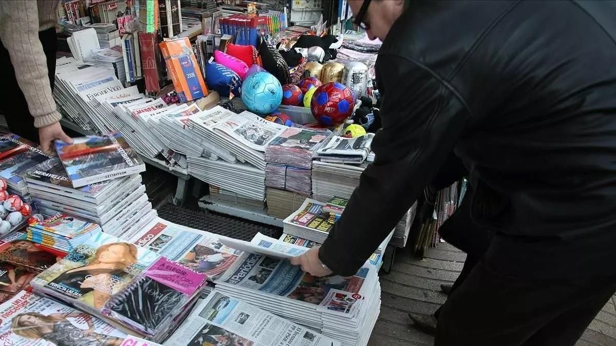 Un hombre compra un periódico en un quiosco.