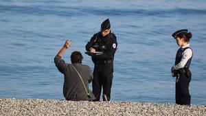 Dos policías de Niza multan a un hombre por estar en la playa, el pasado 19 de marzo.