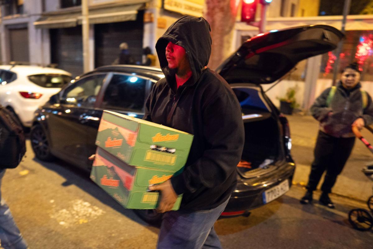 Voluntarios de distintas entidades privadas reparten comida para la cena de Nochebuena bajo la autopista C-31, donde aún duermen decenas de personas desalojadas del antiguo instituto B9