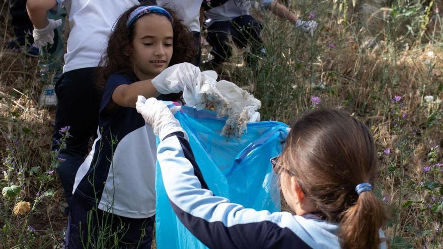 Dos alumnas del colegio Santísima Trinidad recogen basura junto al río Duero. | Ana Burrieza