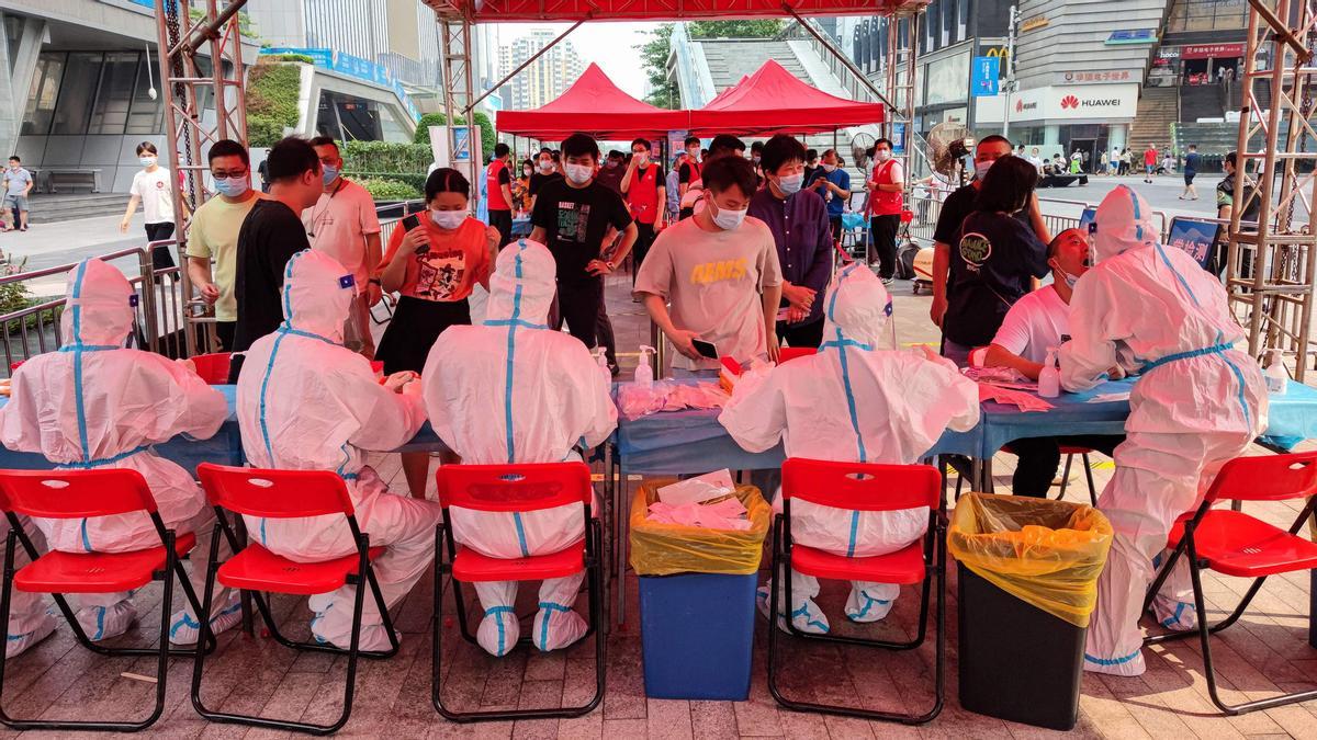 This file photo taken on June 6, 2021 shows people receiving nucleic acid tests for the Covid-19 coronavirus in Shenzhen, in China's southern Guangdong province. - The southern Chinese tech hub Shenzhen was put under a citywide lockdown on March 13, 2022, the local government announced, after it reported 66 new coronavirus cases and sealed off the central business district. (Photo by AFP) / China OUT