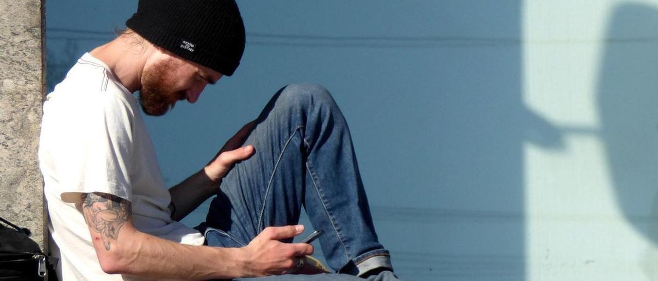 Un chico joven consulta su teléfono móvil.