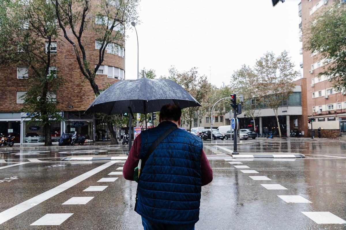 Un hombre se protege de la lluvia con un paraguas en Madrid.