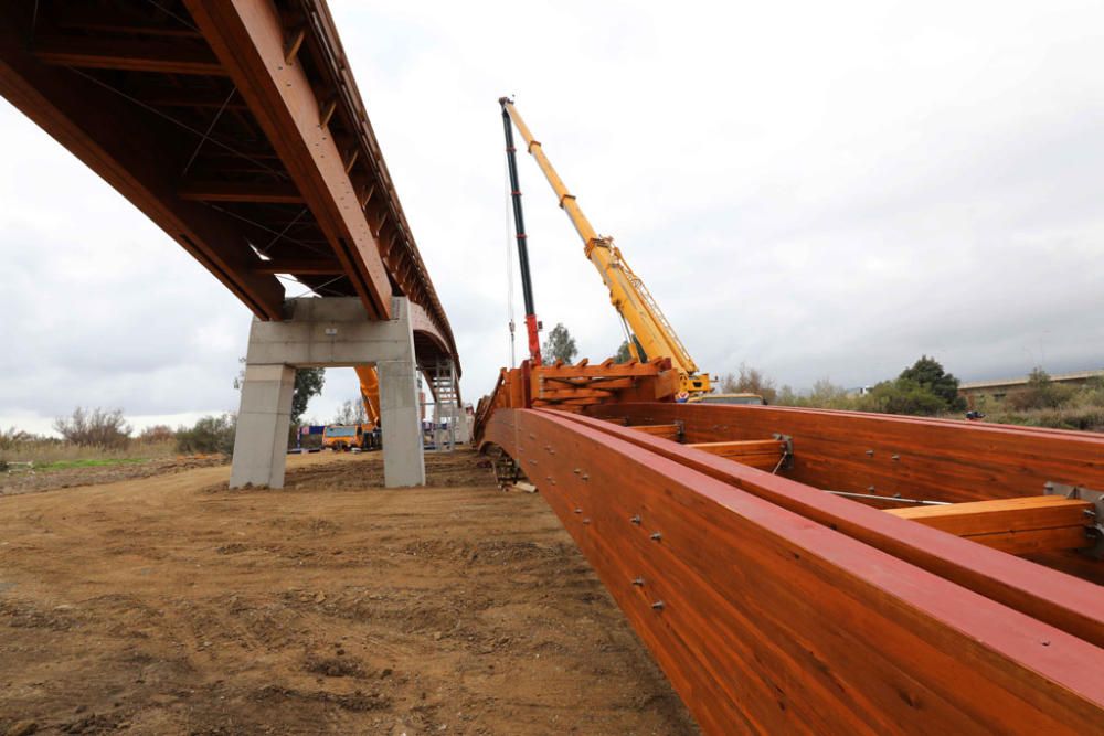 La instalación del último tramo del puente de madera sobre el río Guadalhorce ha comenzado este martes.
