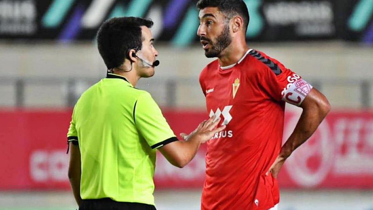 Antonio López, con el brazalete de capitán,  habla con el colegiado durante un partido. | PRENSA REAL MURCIA CF