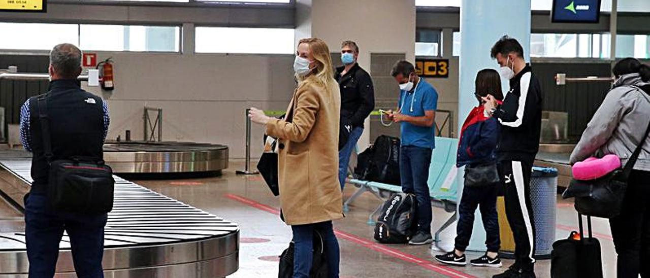 Viajeros esperando las maletas de un vuelo a su llegada a Peinador