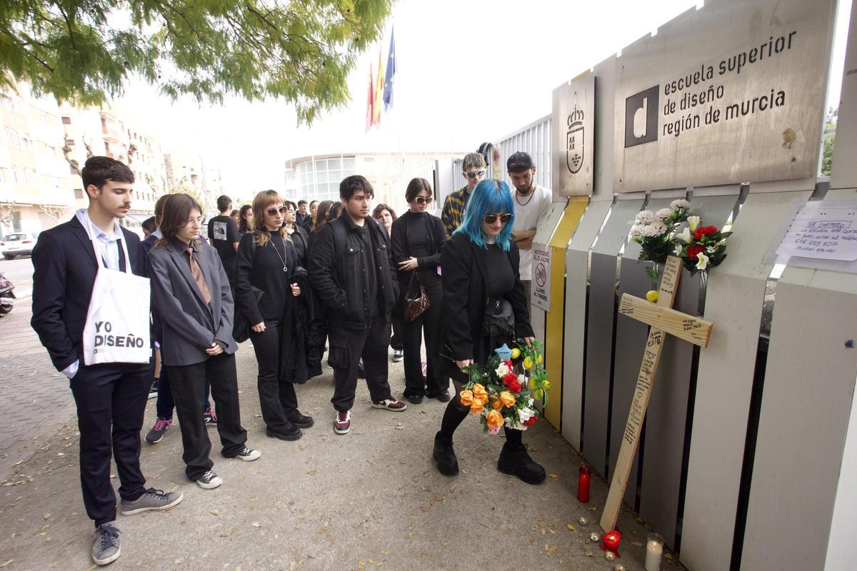 Una alumna deposita flores a las puertas de la EDI, junto al resto de estudiantes vestidos de luto, este miércoles.