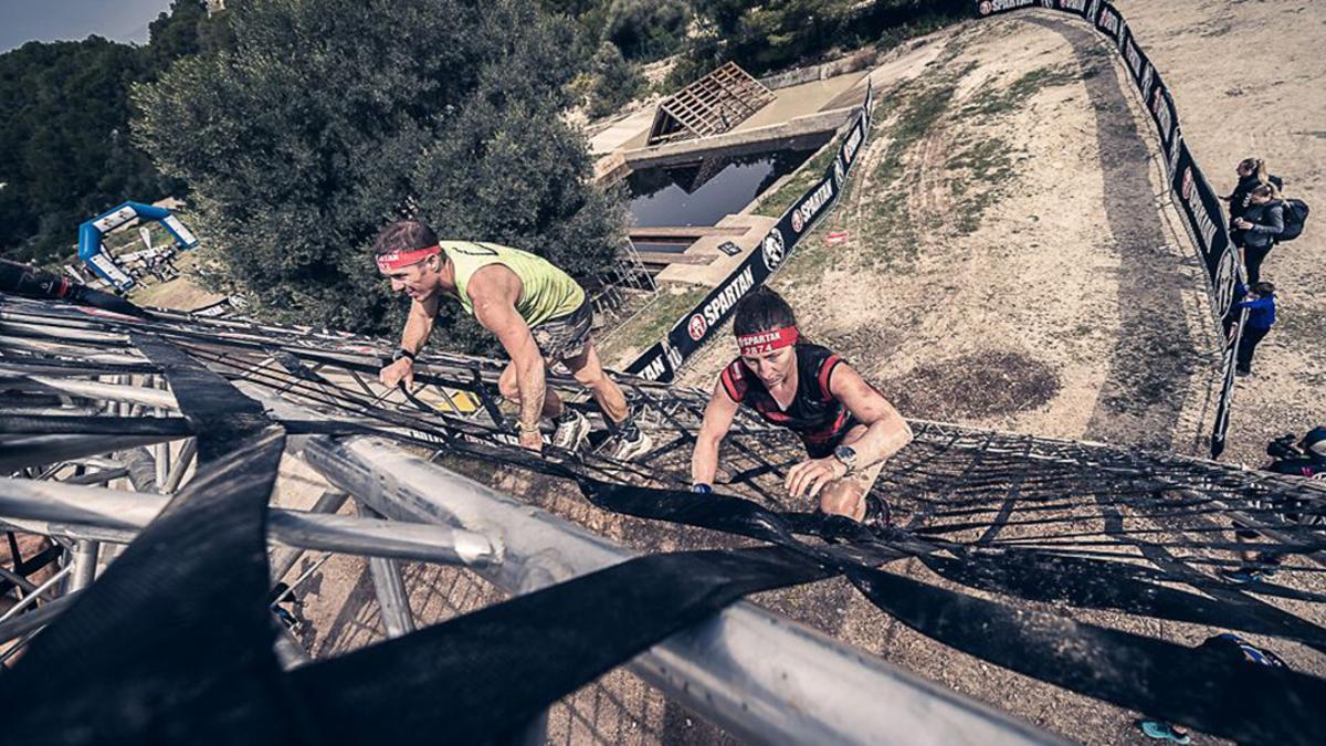 Dos participantes superan un obstáculo de la Spartan Race Mallorca de 2023