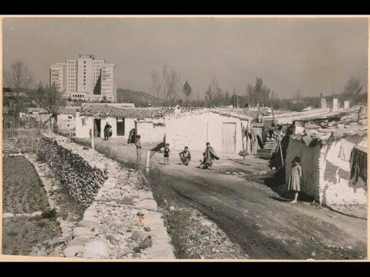 Barraques que acollien la immigració, a Fontajau, amb la Residencia Álvarez de Castro de fons.